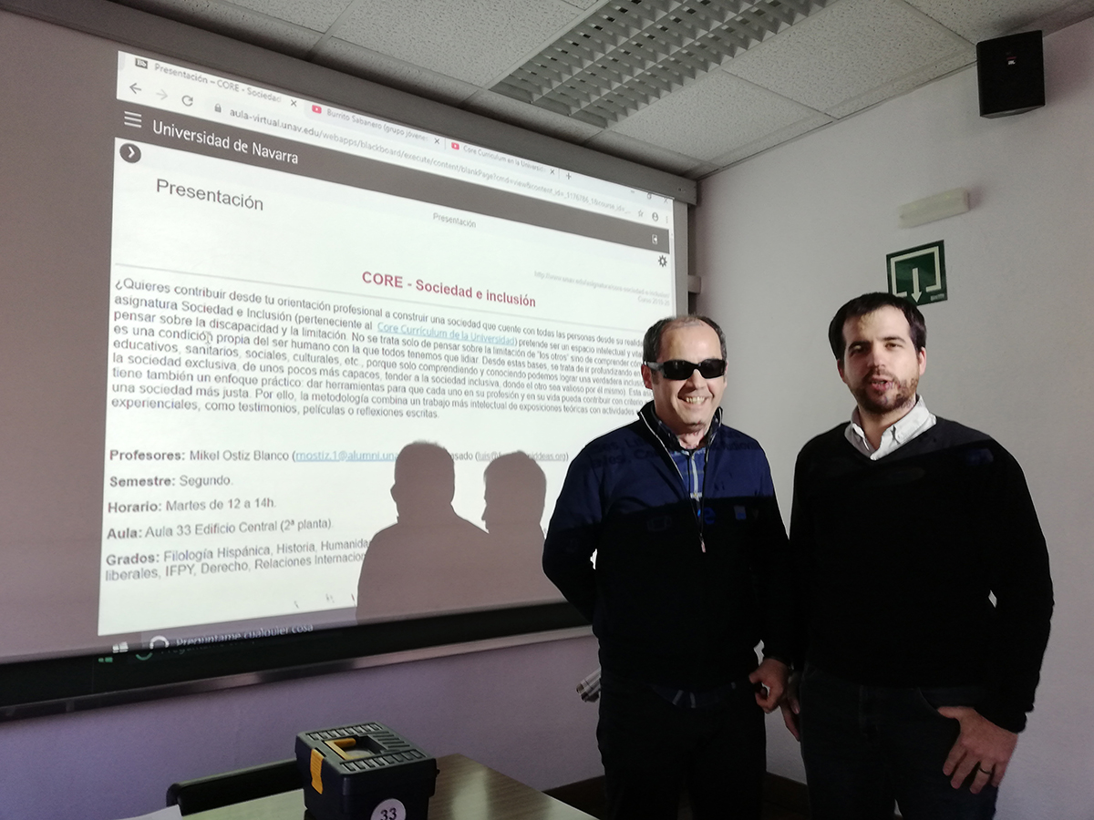 Foto de los profesores Luis Casado y Mikel Ostiz frente a la pantalla donde se proyecta la presentación de la asignatura Sociedad e inclusión, tomada el primer día de clase.